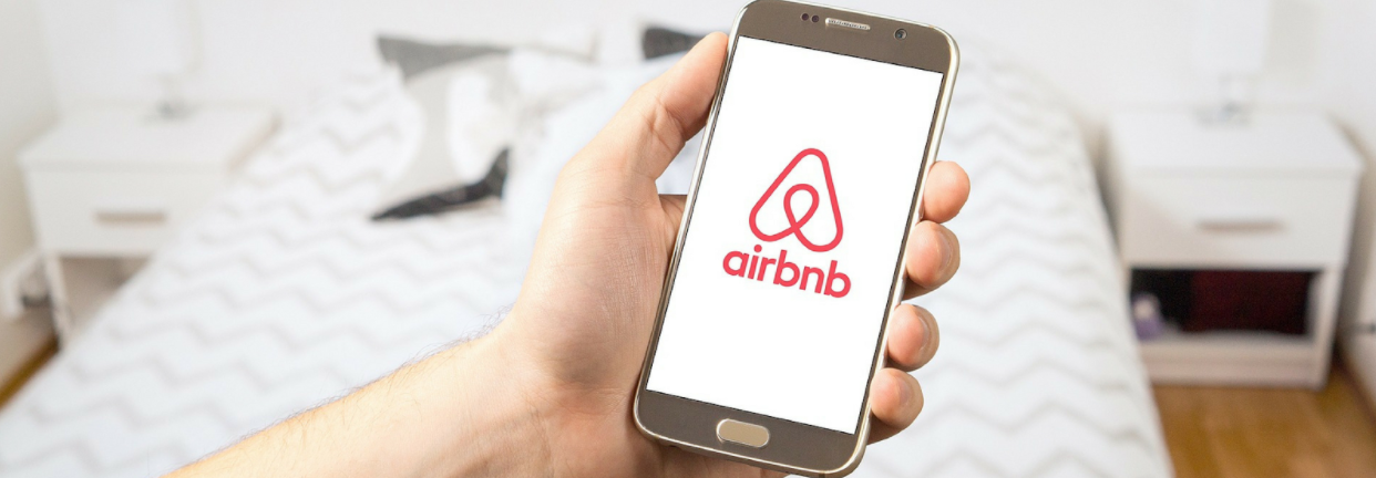 Airbnb logo on phone screen. Airbnb solved the problem of a lack of short term accomodation in busy cities